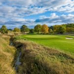Panoramic view of a lush green golf course at Whispering Creek Golf Club. Smooth