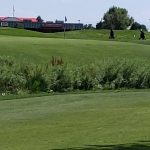 Panoramic view of a lush green golf course at World Golf & Sand Creek Golf Course. Smooth